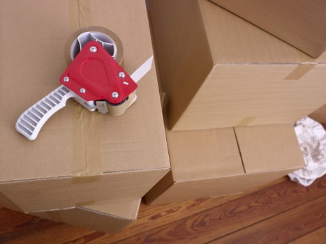 Specialist movers preparing a piano for loading with protective wrapping and straps